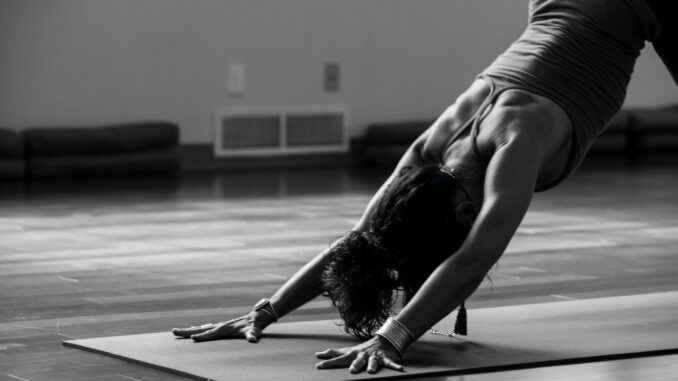 Photo by Ginny Rose Stewart woman in black tank top and black pants bending her body on floor